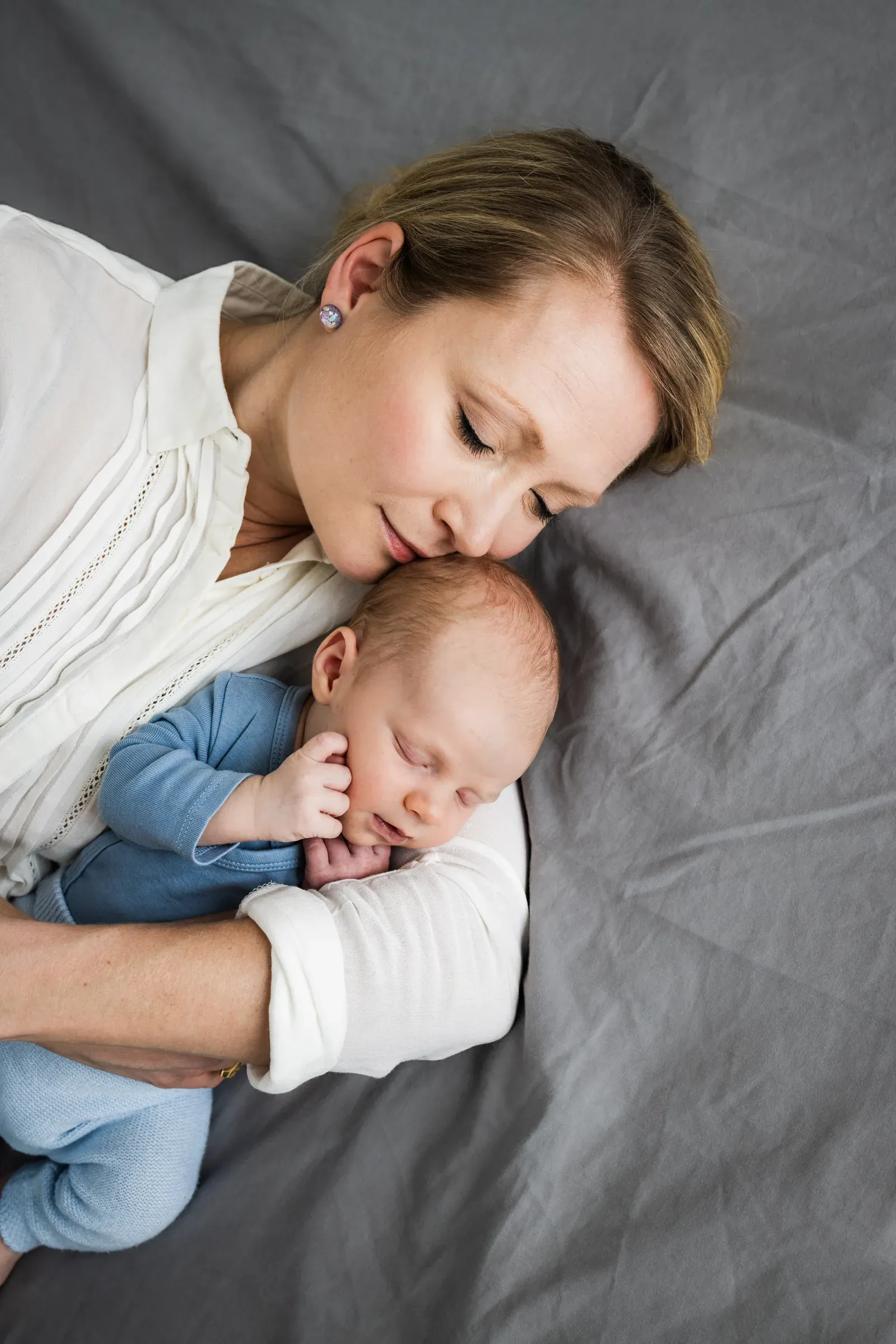 Mags lying beside her newborn, her cheek against his head, eyes closed.
